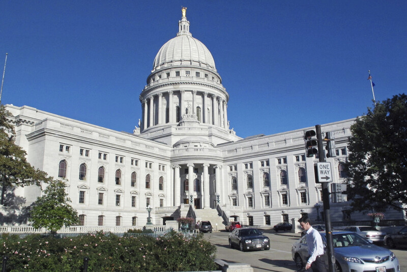 FILE - In this Oct. 10, 2012, file photo, a man walks by the Wisconsin state Capitol in Madison. (AP Photo/Scott Bauer, File)