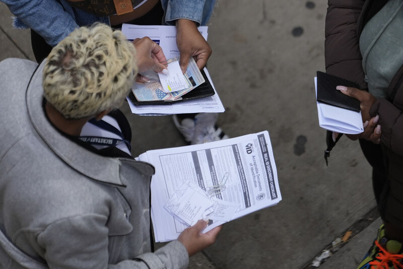 An employee, left, checks on necessary documents as people line up to apply for Real ID at a Real ID Supercenter in downtown Chicago, Tuesday, May 6, 2025. (AP Photo/Kiichiro Sato)