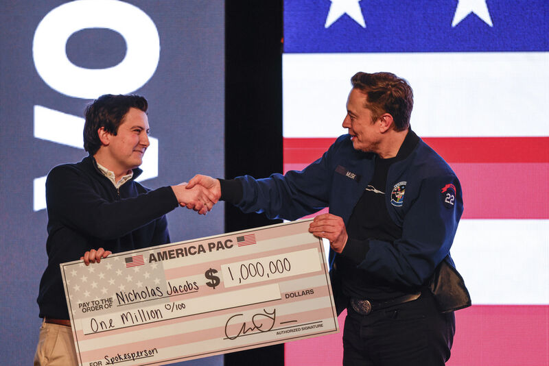 FILE - Elon Musk presents a check for $1 million dollars to a man during a town hall March 30, 2025, in Green Bay, Wis. (AP Photo/Jeffrey Phelps, File)