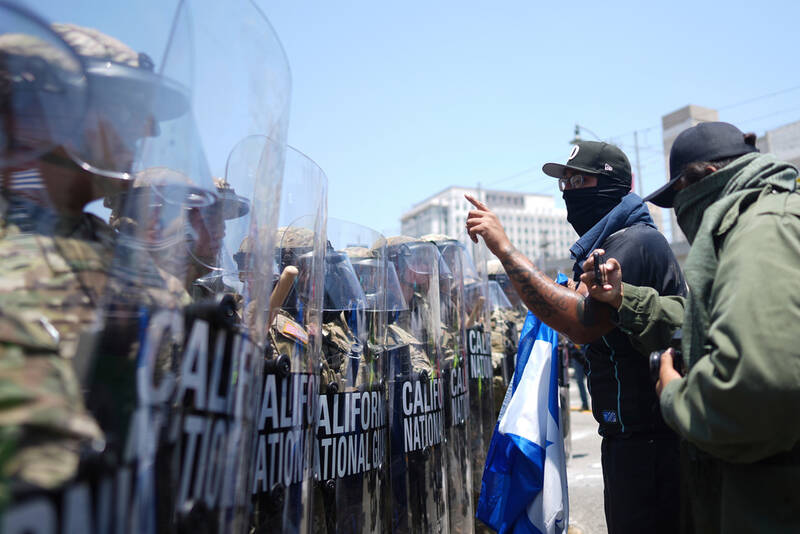 Protesters confront a line of U.S. National Guard in the metropolitan detention center of downtown Los Angeles, Sunday, June 8, 2025, following last night's immigration raid protest. (AP Photo/Eric Thayer)