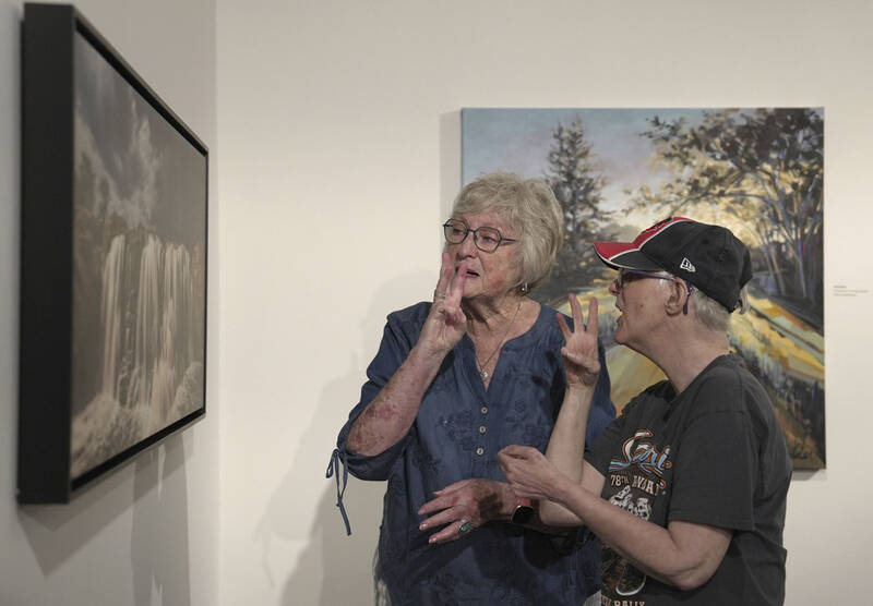 Janith Farnham signs "water" while she and her daughter, Jacque, look at an artwork of a waterfall at the Visual Arts Center at the Washington Pavilion in Sioux Falls, S.D., on May 20, 2025. (AP Photo/Shelby Lum)