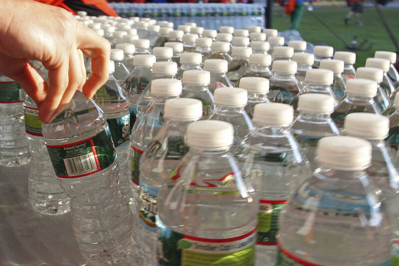 FILE - A runner grabs a bottle of water at the athlete's village prior to the start of the 116th running of the Boston Marathon, in Hopkinton, Mass., April 16, 2012. (AP Photo/Stew Milne, File)