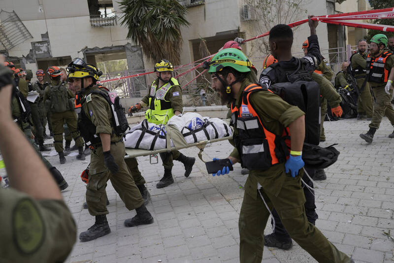 Israeli soldiers and rescue workers carry a body from a residential building destroyed by an Iranian missile strike that killed several people, in Beersheba, Israel, on Tuesday, June 24, 2025. (AP Photo/Bernat Armangue)