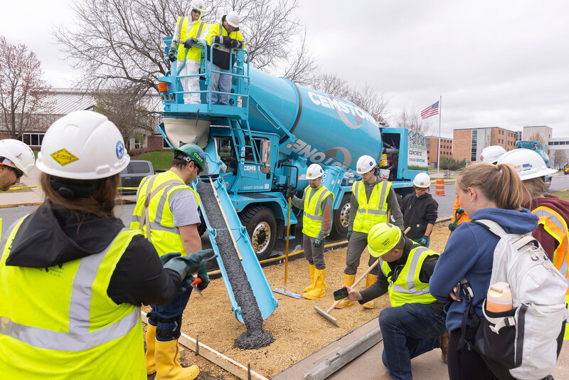 Student Jeremy O'Connor, top left, and Associate Professor Kevin MacDonald watch concrete pour from a ready-mix truck.