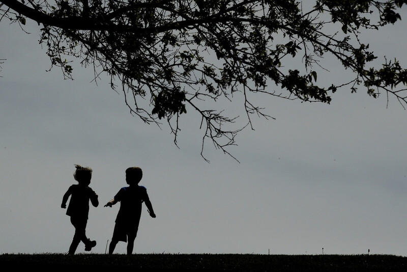 FILE - Children run on the lawn at the Liberty Memorial in Kansas City, Mo., on April 28, 2020. (AP Photo/Charlie Riedel, File)