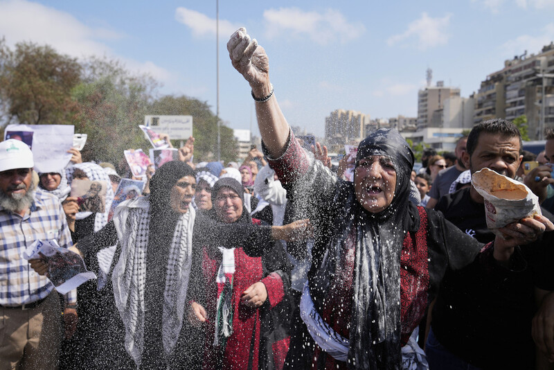 A woman throws flour, as she protests outside the Egyptian Embassy in Beirut, Lebanon, Wednesday, July 23, 2025, during a demonstration against the Israeli war and what they say starvation of civilians in the Gaza Strip. (AP Photo/Hussein Malla)