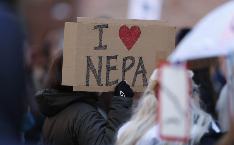 FILE - Joan Lutz, of Boulder, Colo., waves a placard at a rally of advocates to voice opposition to efforts by the Trump administration to weaken the National Environmental Policy Act, which is the country's bedrock law aimed at protecting the environment, on Feb. 11, 2020, in Denver. (AP Photo/David Zalubowski)