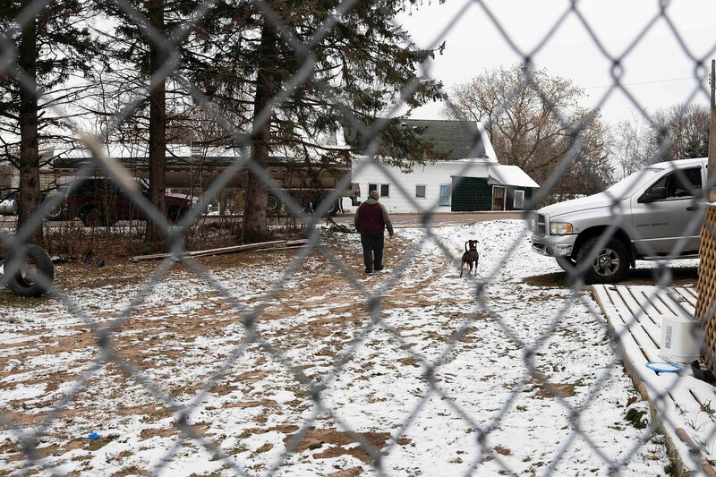 Eric Zieroth walks to his car through the backyard of the apartment where he was staying as his dog, Bella, walks alongside him before driving to his storage unit with his stepdaughter, Christina Hubbell, on Dec. 3, 2024, in Shell Lake, Wis. In the winter, Zieroth and Hubbell moved into a friend’s basement apartment after living in their car for over a year. (Joe Timmerman / Wisconsin Watch)