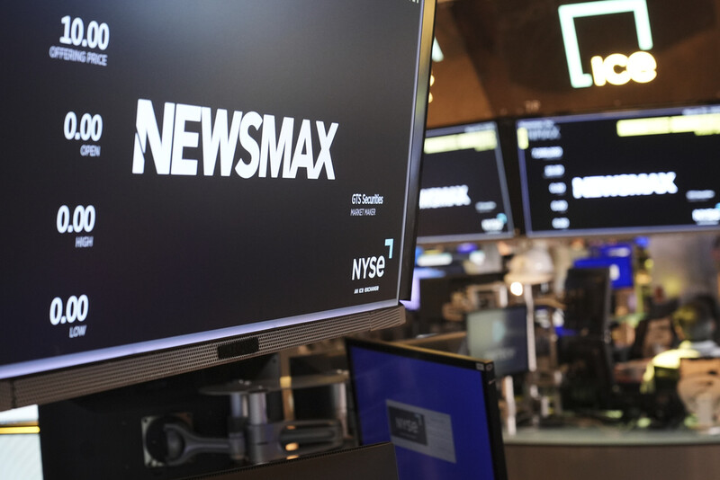 FILE - A display shows a Newsmax logo on the day of their IPO on the floor at the New York Stock Exchange in New York, March 31, 2025. (AP Photo/Seth Wenig, File)