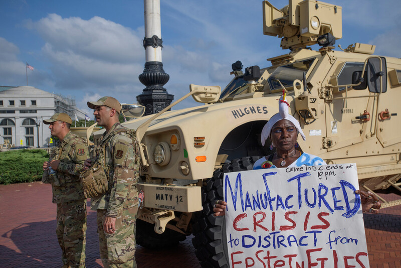 Protester Nadine Seiler holds her sign near National Guard members from the 167th Security Forces from West Virginia, outside Union Station in Washington, Wednesday, Aug. 20, 2025. (AP Photo/Rod Lamkey, Jr.)