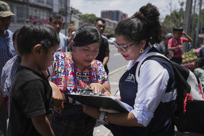 A relative of an unaccompanied minor deported from the United States reviews the list of those deported outside La Aurora International Airport, in Guatemala City, Sunday, Aug. 31, 2025. (AP Photo/Moises Castillo)