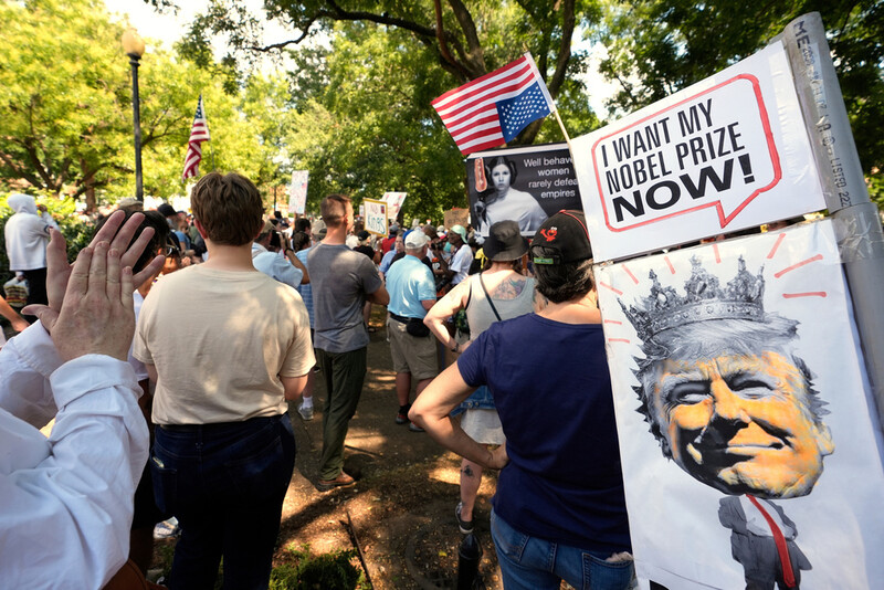 FILE - Activists carry signs during a protest against President Donald Trump's federal takeover of policing of the District of Columbia, Saturday, Aug. 16, 2025, in Washington. (AP Photo/Alex Brandon, File)