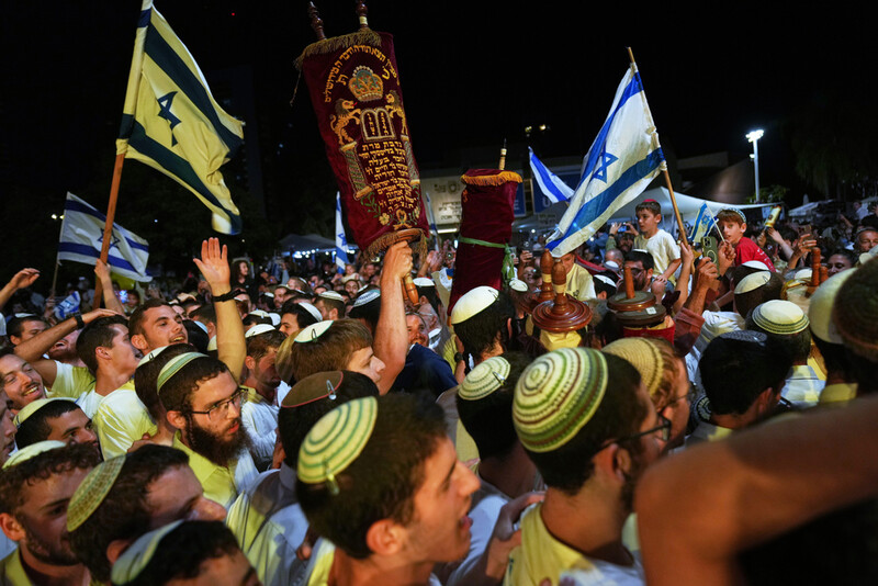 Jewish revelers dance and hold up the Torah as they celebrate the holiday of Simchat Torah at the plaza known as hostages square in Tel Aviv, Israel, Tuesday, Oct. 14, 2025. (AP Photo/Francisco Seco)