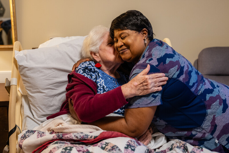 Shirley Warthen, 93, a resident, left, pulls in Jackie Conteh, an advanced care partner originally from Sierra Leone, for a hug in her apartment at Goodwin House Alexandria, Thursday, Oct. 16, 2025, in Alexandria, Va. (AP Photo/Eric Lee)