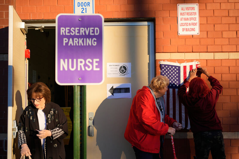 Poll workers Shalanda Esserry, right, and Barbara Zackaroff, center, tape an American flag next to the entrance of a polling site in Garfield, N.J., Tuesday, Nov. 4, 2025. (AP Photo/Seth Wenig)