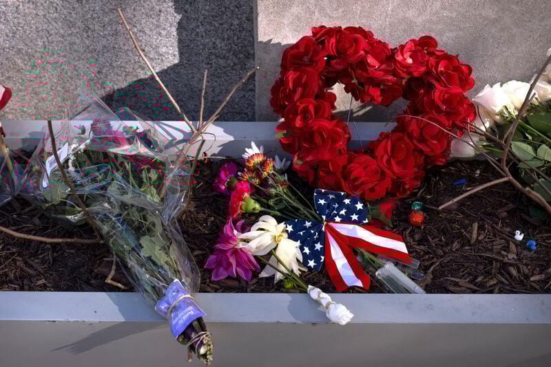 People walk past a small memorial in a planter, Friday, Nov. 28, 2025, near the site where two National Guard members were shot in Washington. (AP Photo/Mark Schiefelbein)