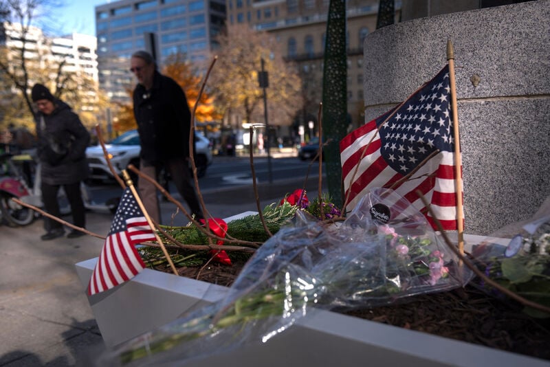 People walk past a small memorial in a planter, Friday, Nov. 28, 2025, near the site where two National Guard members were shot in Washington. (AP Photo/Mark Schiefelbein)