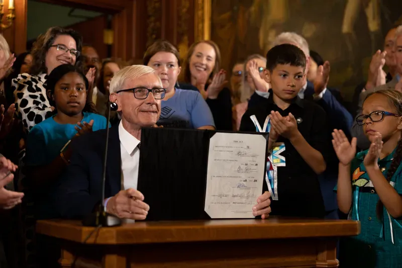 Democratic Wisconsin Gov. Tony Evers displays a two-year budget that he signed July 5, 2023, in Madison, Wis. Evers used his partial veto power to remove tax cuts for the state's wealthiest taxpayers and protect 180 diversity, equity and inclusion jobs Republicans wanted to cut at the University of Wisconsin. (Drake White-Bergey / Wisconsin Watch)