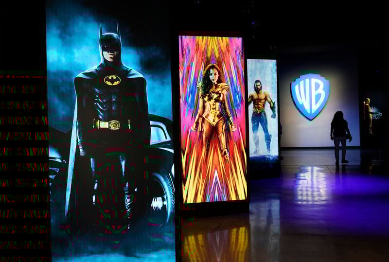 FILE - A visitor walks past portraits of DC Comics superheroes as she enters the "Action and Magic Made Here" interactive experience at the Warner Bros. Studio Tour Hollywood media preview on June 24, 2021, in Burbank, Calif. (AP Photo/Chris Pizzello, File)