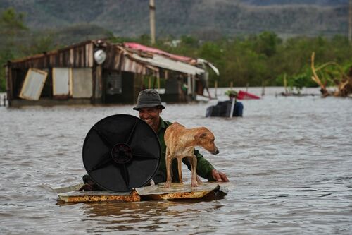 A man wades through floodwaters with his dog and belongings from his home flooded by Hurricane Melissa in Santiago de Cuba, Wednesday, Oct. 29, 2025. (AP Photo/Ramón Espinosa)