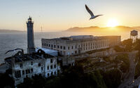 A bird flies above Alcatraz Island on Sunday, May 4, 2025, in the San Francisco Bay, Calif. (AP Photo/Noah Berger)