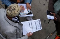 An employee, left, checks on necessary documents as people line up to apply for Real ID at a Real ID Supercenter in downtown Chicago, Tuesday, May 6, 2025. (AP Photo/Kiichiro Sato)