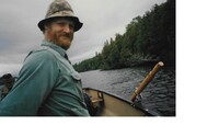 author in a row boat on a wilderness lake