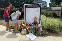 People leave flowers Monday, Aug. 11, 2025, at a makeshift memorial in honor of David Rose, the officer who was killed in the shooting at the U.S. Centers for Disease Control and Prevention headquarters in Atlanta. (AP Photo/Charlotte Kramon)