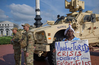 Protester Nadine Seiler holds her sign near National Guard members from the 167th Security Forces from West Virginia, outside Union Station in Washington, Wednesday, Aug. 20, 2025. (AP Photo/Rod Lamkey, Jr.)