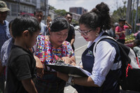 A relative of an unaccompanied minor deported from the United States reviews the list of those deported outside La Aurora International Airport, in Guatemala City, Sunday, Aug. 31, 2025. (AP Photo/Moises Castillo)