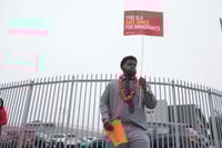 Teacher Naim Muhammad holds a sign supporting immigrants on the first day of school Thursday, Aug. 14, 2025, in Los Angeles. (AP Photo/Marcio Jose Sanchez)