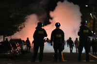 Law enforcement officers stand after deploying tear gas outside a U.S. Immigration and Customs Enforcement facility during a protest on Saturday, Oct. 4, 2025, in Portland, Ore. (AP Photo/Jenny Kane)