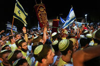 Jewish revelers dance and hold up the Torah as they celebrate the holiday of Simchat Torah at the plaza known as hostages square in Tel Aviv, Israel, Tuesday, Oct. 14, 2025. (AP Photo/Francisco Seco)