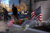 People walk past a small memorial in a planter, Friday, Nov. 28, 2025, near the site where two National Guard members were shot in Washington. (AP Photo/Mark Schiefelbein)
