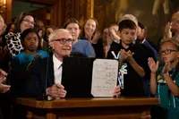 Democratic Wisconsin Gov. Tony Evers displays a two-year budget that he signed July 5, 2023, in Madison, Wis. Evers used his partial veto power to remove tax cuts for the state's wealthiest taxpayers and protect 180 diversity, equity and inclusion jobs Republicans wanted to cut at the University of Wisconsin. (Drake White-Bergey / Wisconsin Watch)