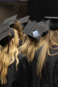 A student decorates their cap at commencement with the Stout logo.
