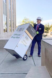 n this photo provided by Wausau Mayor Doug Diny, Diny uses a dolly to remove the city's lone drop box from in front of City Hall in Wausau, Wis., on Sunday, Sept. 22, 2024. (Doug Diny via AP)