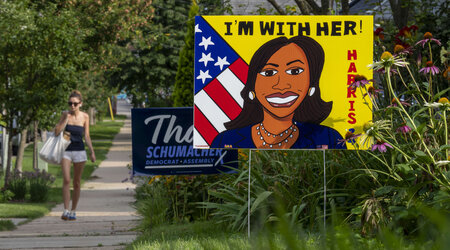 A pedestrian walks along the sidewalk past a sign in support of Kamala Harris on Tuesday, July 30, 2024, in Madison, Wis. (AP Photo/Kayla Wolf)