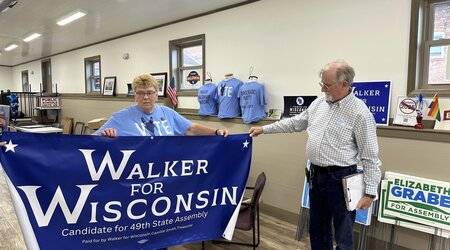 Grant County Democratic Party Chair Joyce Bos, left, and Democratic legislative candidate Scott Abbot Walker inspect a campaign banner Friday, Sept. 6, 2024, in the county party headquarters in Platteville, Wis. (AP Photo/Todd Richmond)