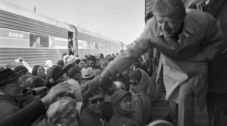 FILE - President-elect Jimmy Carter leans over to shake hands with some of the people riding the &quot;Peanut Special&quot; to Washington, Jan. 19, 1977. They will travel all night, arriving in Washington in time for Carter's inauguration as president on Jan. 20. (AP Photo, File)