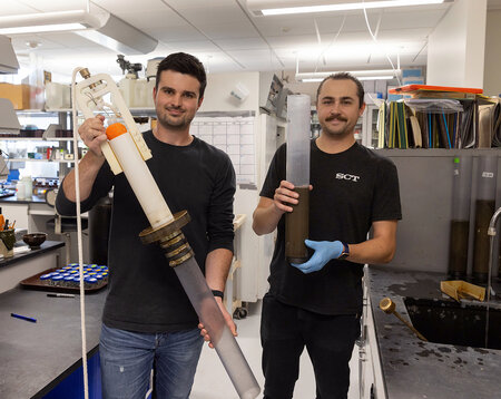 CLRR Field Coordinator Andrew Schneyer, left, and Laboratory Coordinator Conor Dougherty show a gravity coring device like the one used to take sediment cores on Green Lake in Wisconsin. Conor is holding an intact sediment core.