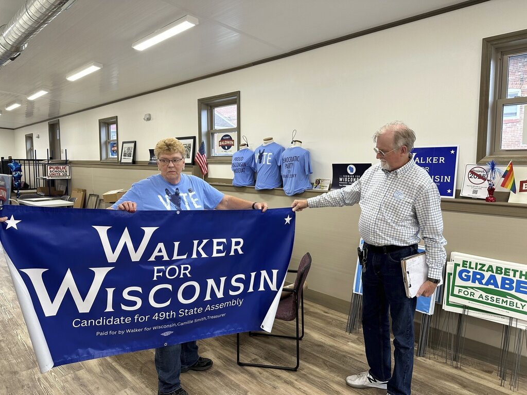 Grant County Democratic Party Chair Joyce Bos, left, and Democratic legislative candidate Scott Abbot Walker inspect a campaign banner Friday, Sept. 6, 2024, in the county party headquarters in Platteville, Wis. (AP Photo/Todd Richmond)