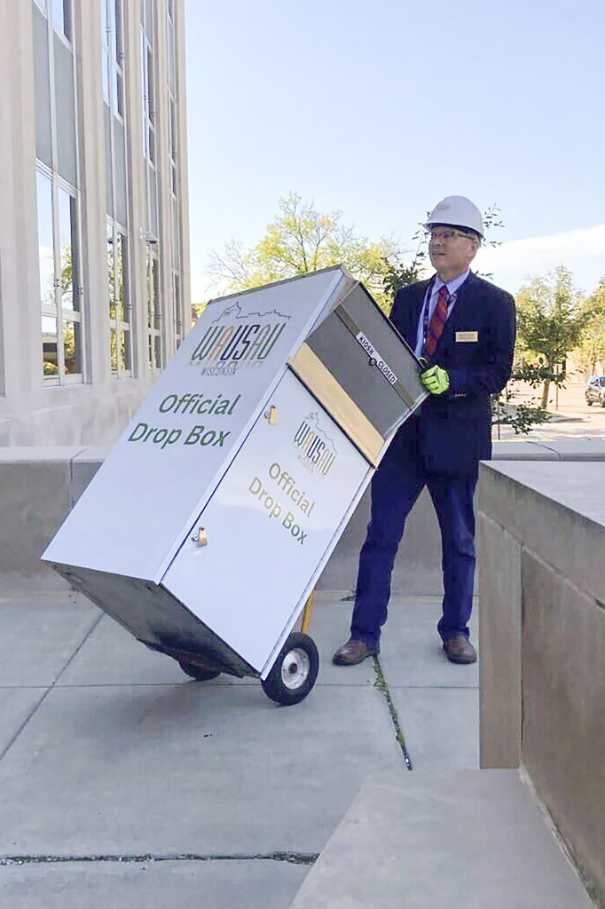 n this photo provided by Wausau Mayor Doug Diny, Diny uses a dolly to remove the city's lone drop box from in front of City Hall in Wausau, Wis., on Sunday, Sept. 22, 2024. (Doug Diny via AP)