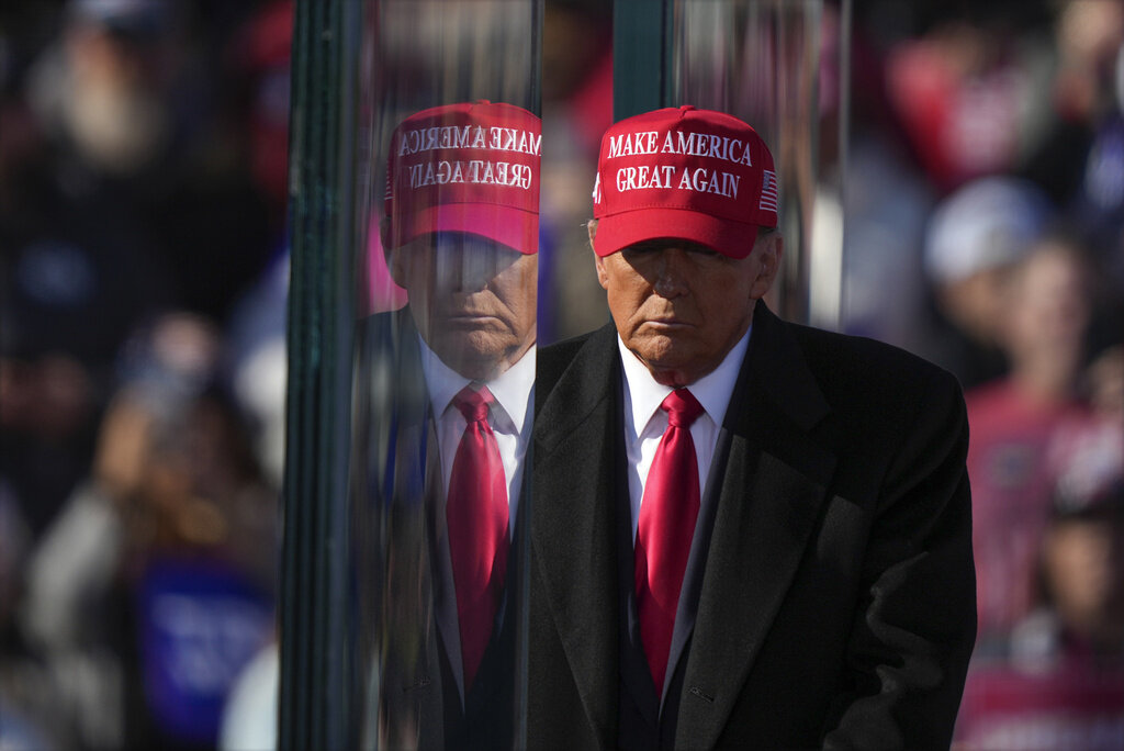 Republican presidential nominee former President Donald Trump is reflected in the bullet proof glass as he finishes speaking at a campaign rally in Lititz, Pa., Sunday, Nov. 3, 2024. (AP Photo/Matt Rourke)